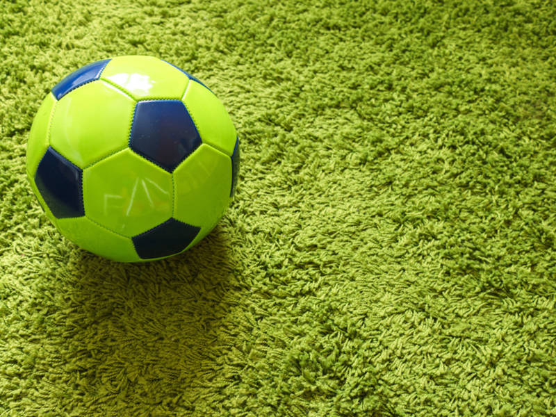 Football (Soccer) ball on a green surface imitating artificial grass. Sports photography; Shutterstock ID 1034235352