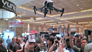 Drone flying over a crowd of people who are taking photos of the drone.